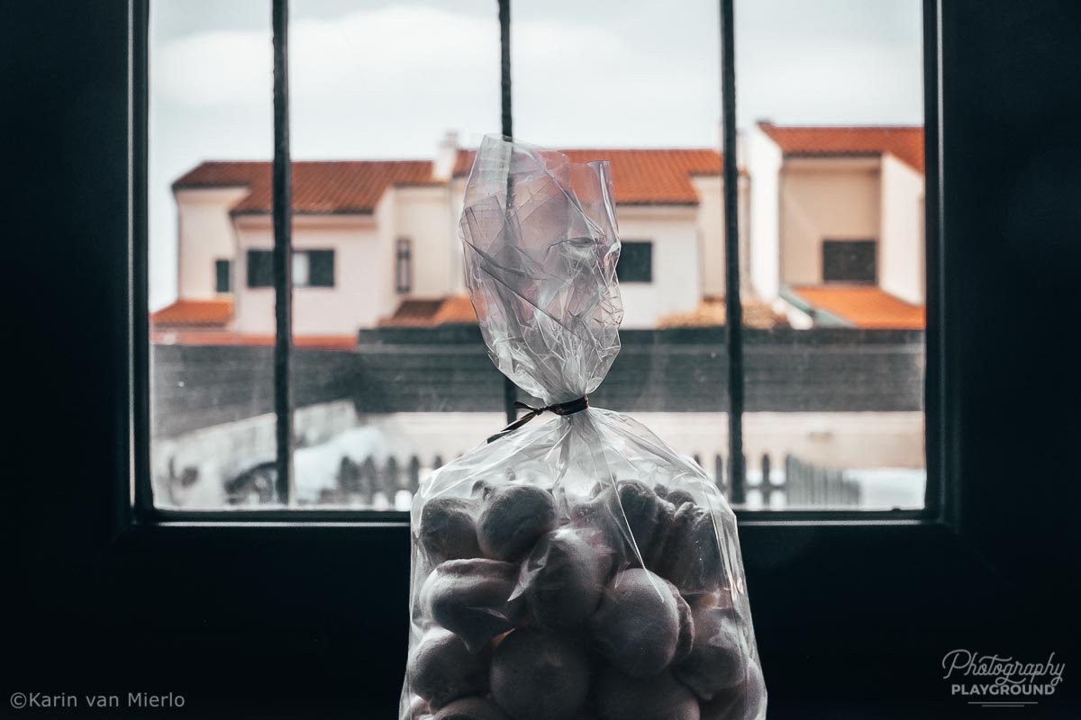 Photography Project: 9 photos of the same object, famous photography projects, creative photography ideas| Photo: a bag of meringues with houses in the background ©Karin van Mierlo. Photography Playground