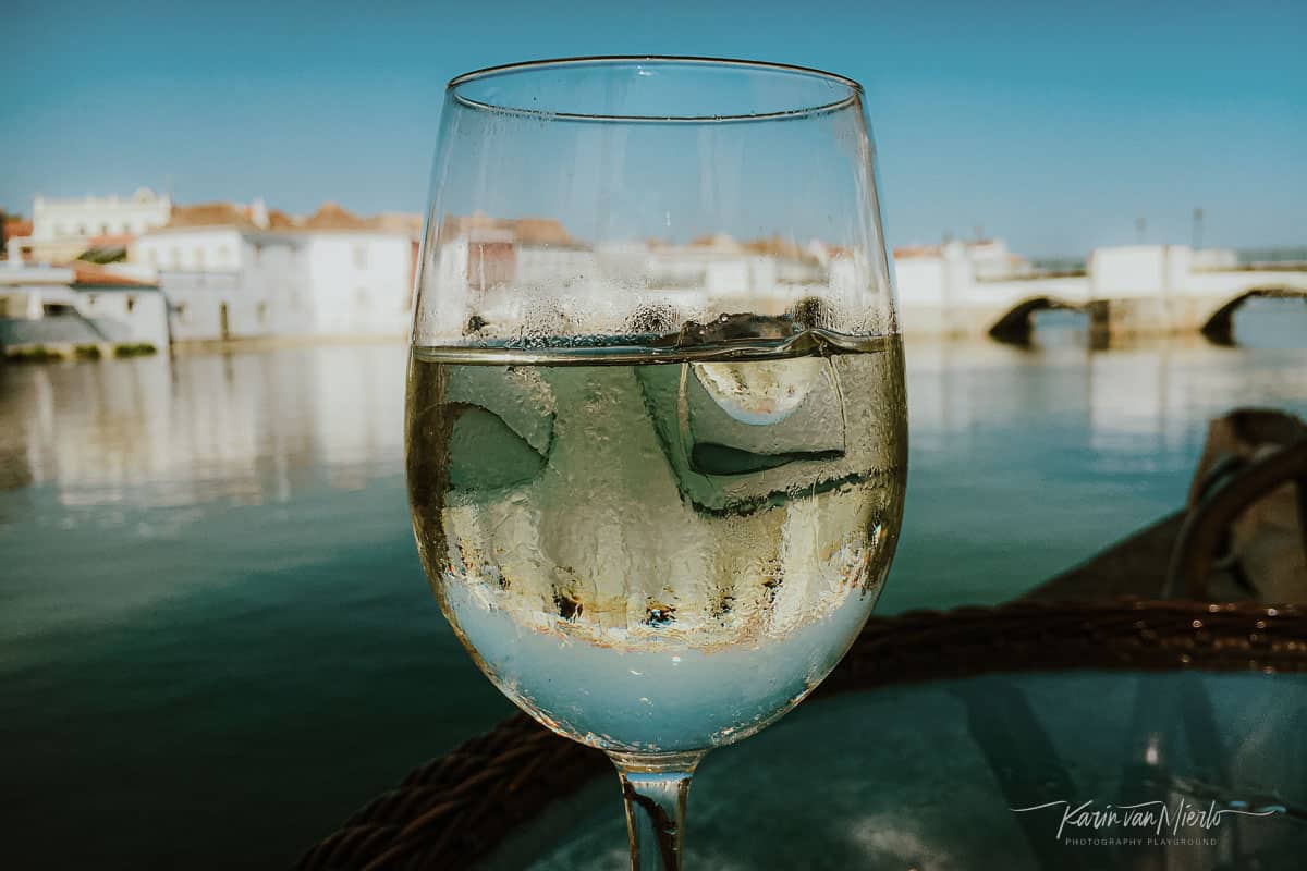 summer photography ideas | Copyright Karin van Mierlo, Photography Playground. Photo: A glass of chilled white wine against the town of Tavira, Portugal